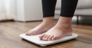 A person stands on an electronic scale during a weight measurement. (Shutetrstock Photo)