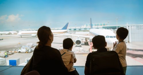 A family with kids looks at airplanes in a terminal while waiting for their flight, Changi Airport, Singapore. (Shutterstock Photo)