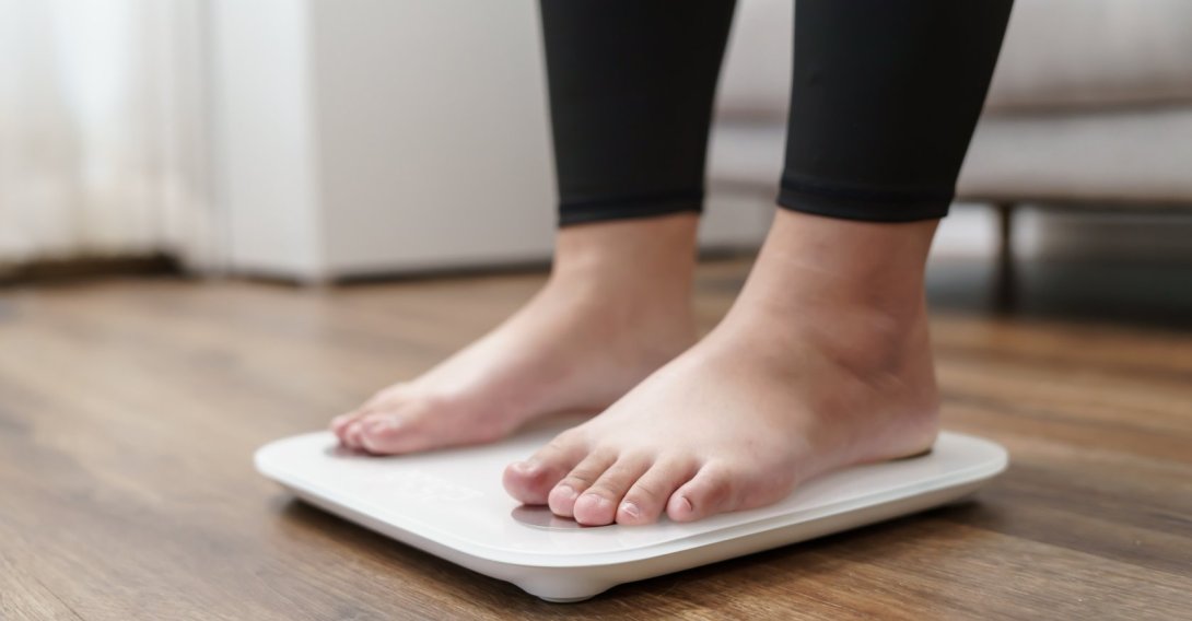 A person stands on an electronic scale during a weight measurement. (Shutetrstock Photo)