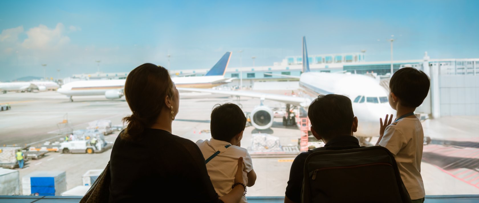 A family with kids looks at airplanes in a terminal while waiting for their flight, Changi Airport, Singapore. (Shutterstock Photo)