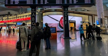 Passengers look at flight information boards after landing at Istanbul Airport in Istanbul, Türkiye, March 12, 2026. (Reuters Photo)