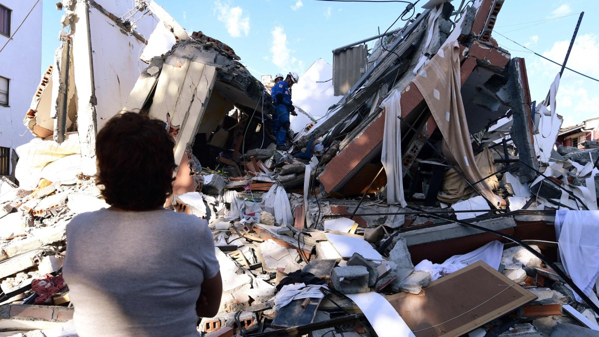 A woman looks at rescuers searching for survivors amid the rubble of a collapsed building after an earthquake, Pereira, Colombia, Aug. 10, 2026. (AFP Photo)
