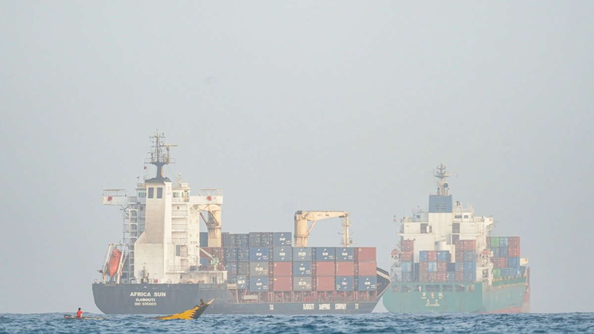People sail their boat past container ships anchoring near the Strait of Bab al-Mandeb off Yemen's coast in the Gulf of Aden, Aug. 6, 2026. (AFP Photo) 