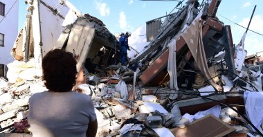 A woman looks at rescuers searching for survivors amid the rubble of a collapsed building after an earthquake, Pereira, Colombia, Aug. 10, 2026. (AFP Photo)