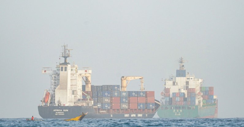 People sail their boat past container ships anchoring near the Strait of Bab al-Mandeb off Yemen's coast in the Gulf of Aden, Aug. 6, 2026. (AFP Photo) 