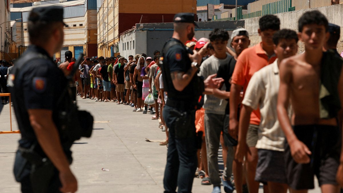 Migrants queue to receive food staples from local NGO Media Luna Blanca in an industrial area where they are sleeping amid recent mass crossings by migrants on foot and by sea from Morocco into the Spanish territory, in Ceuta, Spain, Aug. 6, 2026. (Reuters Photo)
