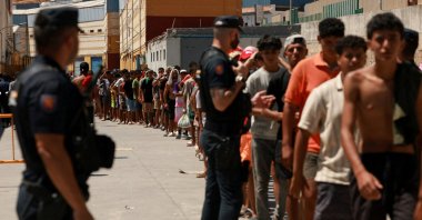 Migrants queue to receive food staples from local NGO Media Luna Blanca in an industrial area where they are sleeping amid recent mass crossings by migrants on foot and by sea from Morocco into the Spanish territory, in Ceuta, Spain, Aug. 6, 2026. (Reuters Photo)