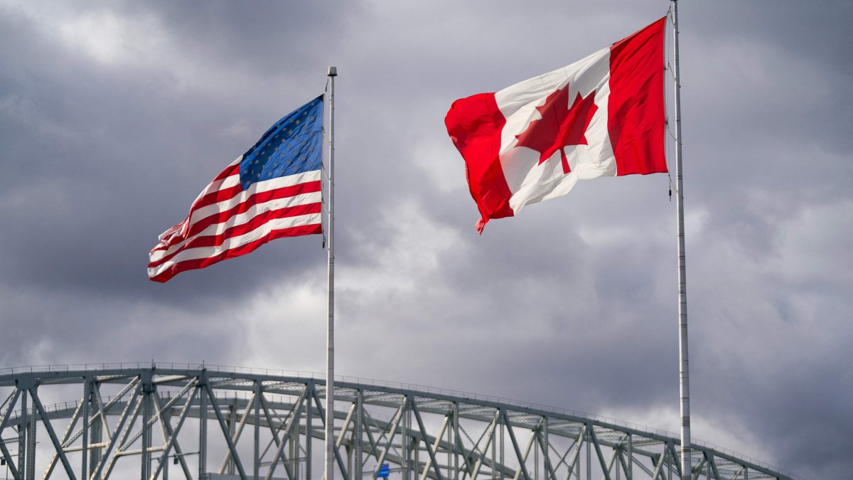 The U.S. and Canada flags flutter next to the Blue Water Bridge border crossing in Point Edward, Ontario, Oct. 24, 2025. (AFP Photo)