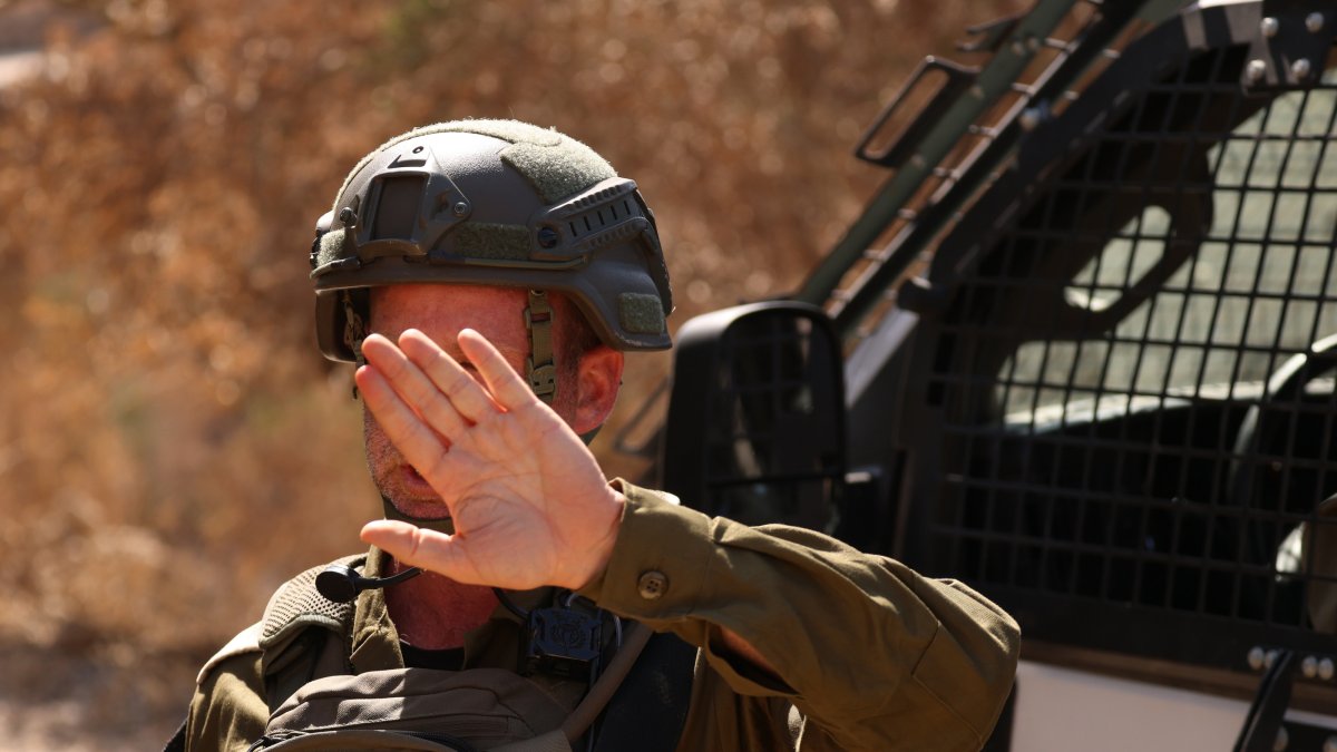 An Israeli soldier blocks a road as illegal Israeli settlers besiege a Palestinian home for the fourth consecutive day in the town of Qusra, south of Nablus, Aug.13, 2026. (EPA Photo)