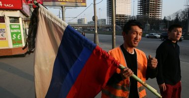 Migrant municipal workers from Kyrgyzstan install Russian flags with black mourning bands on the buildings, Moscow, Russia, April, 11, 2010. (Getty Images Photo)