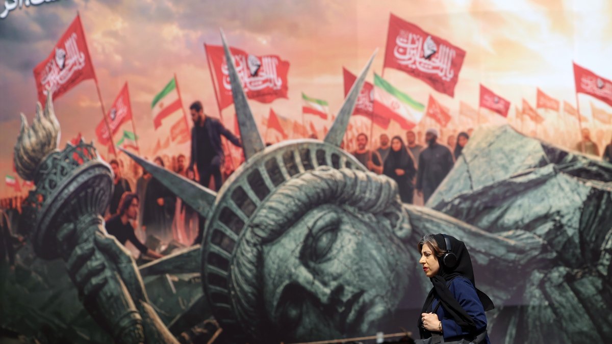 An Iranian woman walks next to an anti-U.S. billboard at Enghelab Square, Tehran, Iran, Aug. 13, 2026. (EPA Photo)