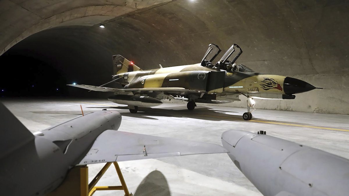 In this picture, released Feb. 7, 2023, by the official website of the Iranian Army, a fighter jet taxis as two drones are seen in the foreground at the Oghab-44, or Eagle-44, underground airbase in an undisclosed location in Iran. (AP Photo)