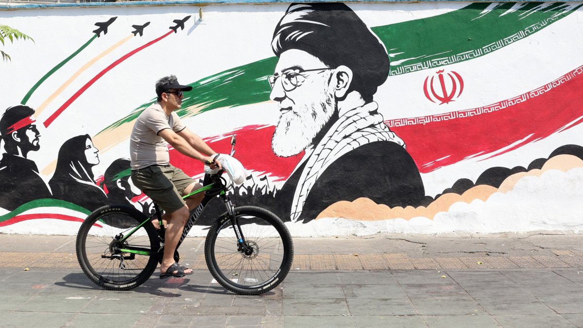 An Iranian man passes with his bike next to a wall painting featuring late Iranian supreme leader Ayatollah Ali Khamenei in a street in central Tehran, Iran, Aug. 13, 2026. (EPA Photo)