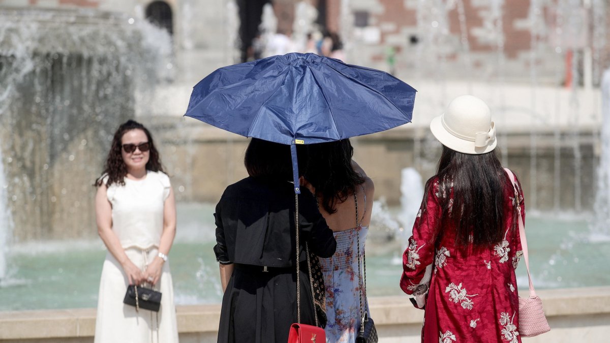 People shelter from the sun under an umbrella on a hot summer day, Milan, Italy, 31 July 2026. (EPA Photo)