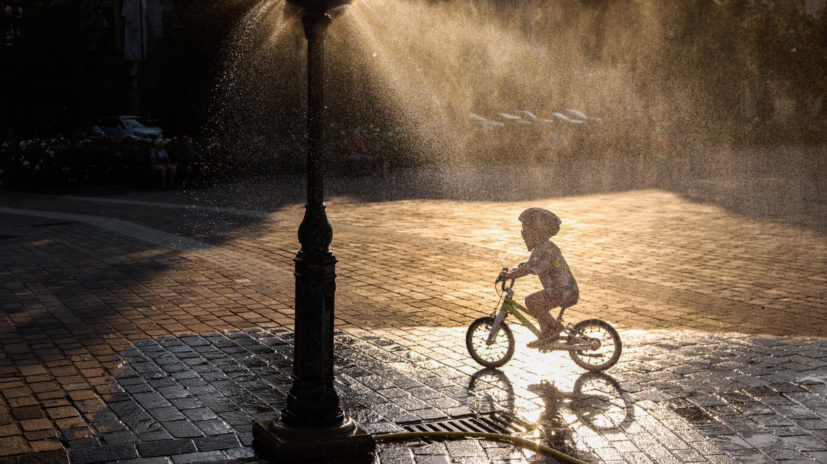 A child rides a bicycle by a water sprinkler at Podgorski Square amid a heat wave that pushed temperatures to 40 degrees Celsius, Krakow, Poland, Aug. 3, 2026. (Getty Images Photo)