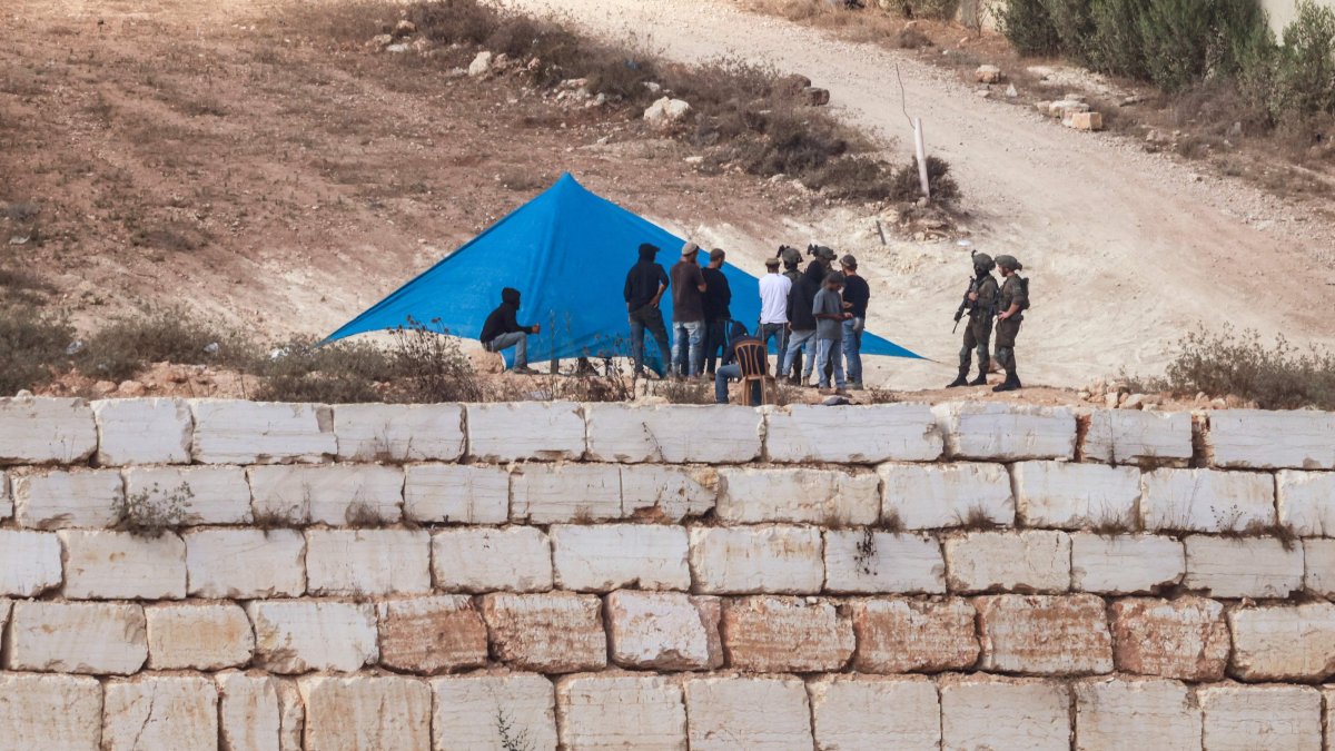 Israeli soldiers are seen as Israeli settlers set up a tent just outside the entrance of a besieged Palestinian family home in the village of Qusra, south of the city of Nablus, in the Israeli-occupied West Bank, Palestine, Aug. 14, 2026. (AFP Photo)