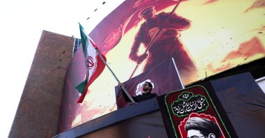 A man holds an Iranian flag, next to a picture of Iran's Supreme Leader Mojtaba Khamenei in Tehran, Iran, Aug. 13, 2026. (Reuters Photo)