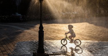A child rides a bicycle by a water sprinkler at Podgorski Square amid a heat wave that pushed temperatures to 40 degrees Celsius, Krakow, Poland, Aug. 3, 2026. (Getty Images Photo)