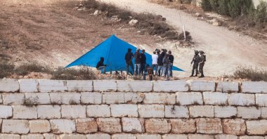 Israeli soldiers are seen as Israeli settlers set up a tent just outside the entrance of a besieged Palestinian family home in the village of Qusra, south of the city of Nablus, in the Israeli-occupied West Bank, Palestine, Aug. 14, 2026. (AFP Photo)