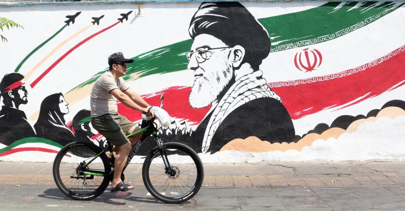 An Iranian man passes with his bike next to a wall painting featuring late Iranian supreme leader Ayatollah Ali Khamenei in a street in central Tehran, Iran, Aug. 13, 2026. (EPA Photo)