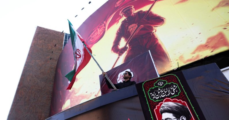 A man holds an Iranian flag, next to a picture of Iran's Supreme Leader Mojtaba Khamenei in Tehran, Iran, Aug. 13, 2026. (Reuters Photo)