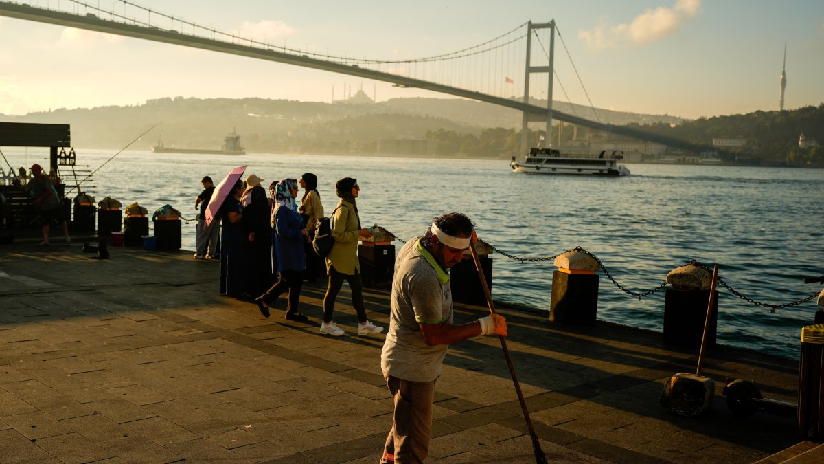 A municipal worker sweeps the sea promenade near the July 15th Martyr bridge, Istanbul, Türkiye, June 26, 2026. (AP Photo)