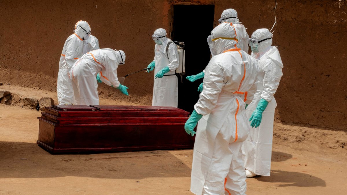 Community-based health workers in personal protective equipment (PPE) disinfect a wooden coffin carrying the body of a man who died of Ebola in Bunia, Congo, July 10, 2026. (Reuters Photo)