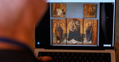 A journalist browses the Messina museum website showing a picture of the Early Renaissance painter Antonello da Messina's artwork, where three of the five panels belonging to the Polyptych of San Gregorio and the double-sided panel with the Madonna and the Christ in Pietà, stolen from the Sicilian museum on Aug. 15, Rome, Italy, Aug. 16, 2026. (AP Photo)