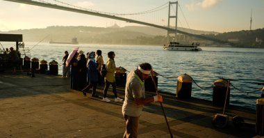 A municipal worker sweeps the sea promenade near the July 15th Martyr bridge, Istanbul, Türkiye, June 26, 2026. (AP Photo)