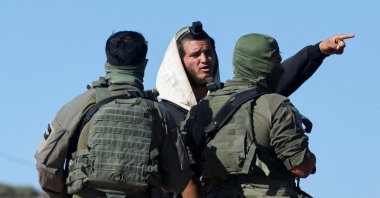 Israeli soldiers speak to an Israeli militant settler who entered Palestinian-American Louay Abu Rida's property in Qusra, the Israeli-occupied West Bank, Aug. 18, 2026. (Reuters Photo)
