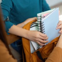 A mother helps her child pack school supplies into a backpack ahead of the new academic year. (Shutterstock Photo)