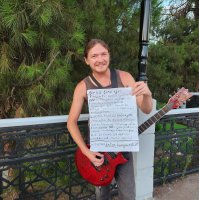 Nikolay Gromkov plays guitar while displaying his handwritten Turkish note, Samsun, Türkiye, Aug. 19, 2026. (IHA Photo)
