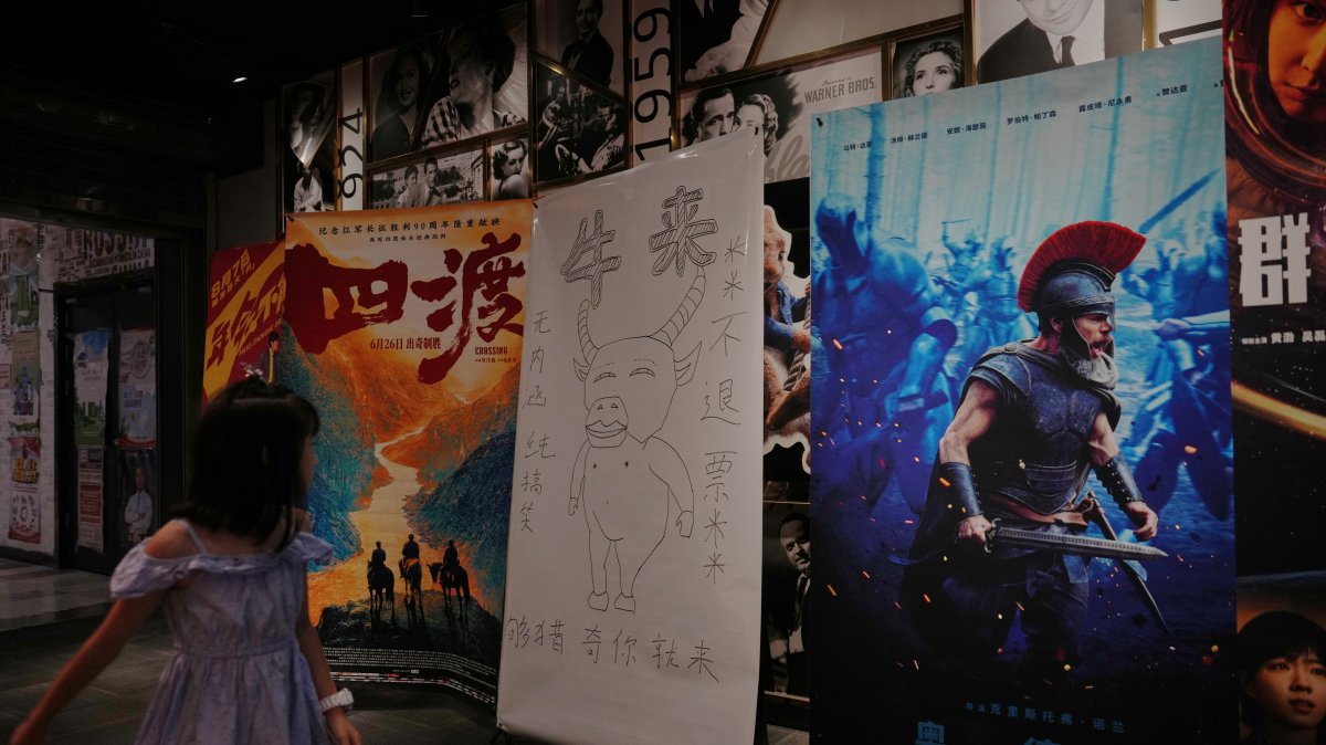 A child looks at a drawing poster promoting a Chinese animated film "Niu Lai" on display with other movie posters at a cinema, Beijing, China, Aug. 18, 2026. (AP Photo)