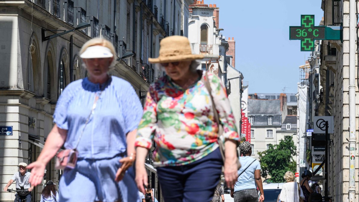 People walk down a street as a pharmacy thermometer indicates a temperature of 36 Celsius degrees as a heat wave hits France, downtown Nantes, France, June 19, 2025. (AFP Photo)