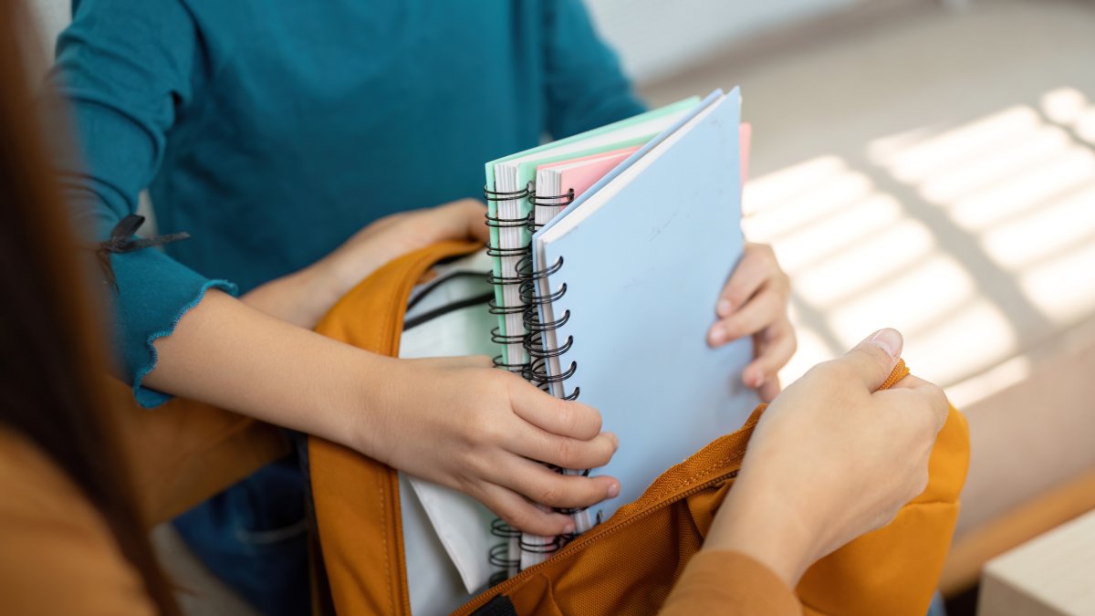 A mother helps her child pack school supplies into a backpack ahead of the new academic year. (Shutterstock Photo)
