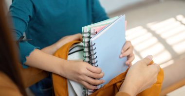 A mother helps her child pack school supplies into a backpack ahead of the new academic year. (Shutterstock Photo)