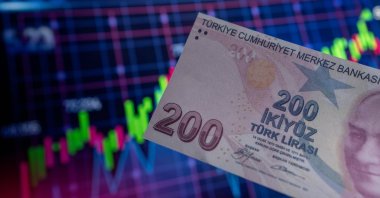 In this photo illustration, a 200 Turkish lira banknote is displayed in front of an economic chart, Türkiye, July 24, 2023. (Reuters Photo)