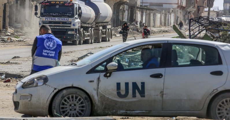 A UNRWA worker leans on a U.N. vehicle as trucks loaded with humanitarian aid cross into the Gaza Strip near Rafah, Gaza, Feb. 17, 2025. (Getty Images Photo)
