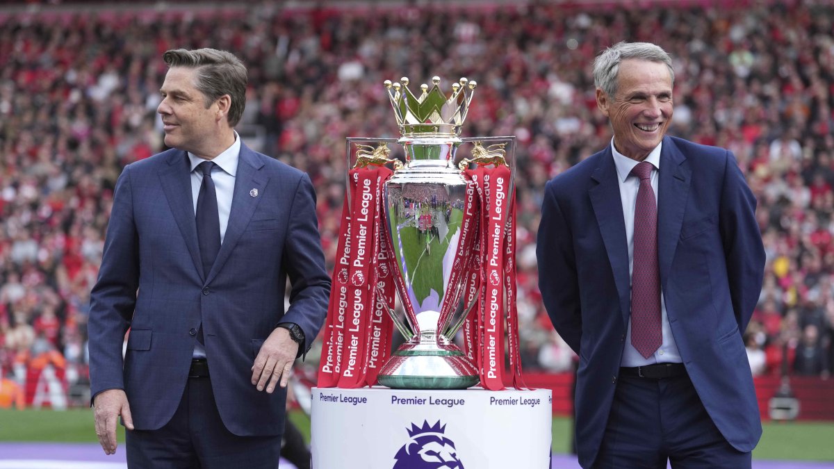 Premier League Chief Executive Officer Richard Masters (L) and former footballer Alan Hansen pose with the winner's trophy after the English Premier League match between Liverpool and Crystal Palace at Anfield Stadium, Liverpool, U.K., May 25, 2025. (AP Photo)