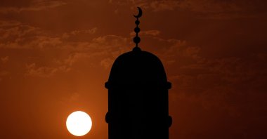The minaret of a mosque is silhouetted by the setting sun, Doha, Qatar, July 28, 2026. (AFP Photo)
