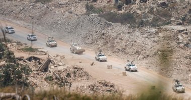 This picture, taken from a position in northern Israel, near the border with Lebanon, shows United Nations Interim Force in Lebanon (UNIFIL) armored vehicles driving past destroyed buildings in southern Lebanon, July 22, 2026. (AFP File Photo)