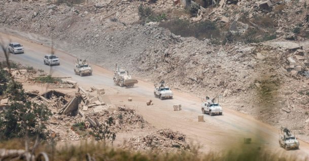 This picture, taken from a position in northern Israel, near the border with Lebanon, shows United Nations Interim Force in Lebanon (UNIFIL) armored vehicles driving past destroyed buildings in southern Lebanon, July 22, 2026. (AFP File Photo)
