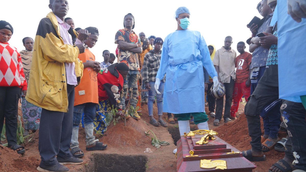 Mourners gather around the coffin of Baudo Baraka Jules as a person wearing protective clothing stands nearby during his burial at Nyamurongo Cemetery, Bunia, DRC, Aug. 18, 2026. (EPA Photo)