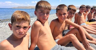 Children sit on the shore of Lake Van, eastern Türkiye, Aug. 21, 2026. (İHA Photo)