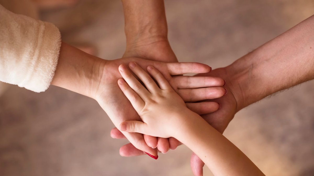 Four hands come together, symbolizing family unity. (Shutterstcok Photo)