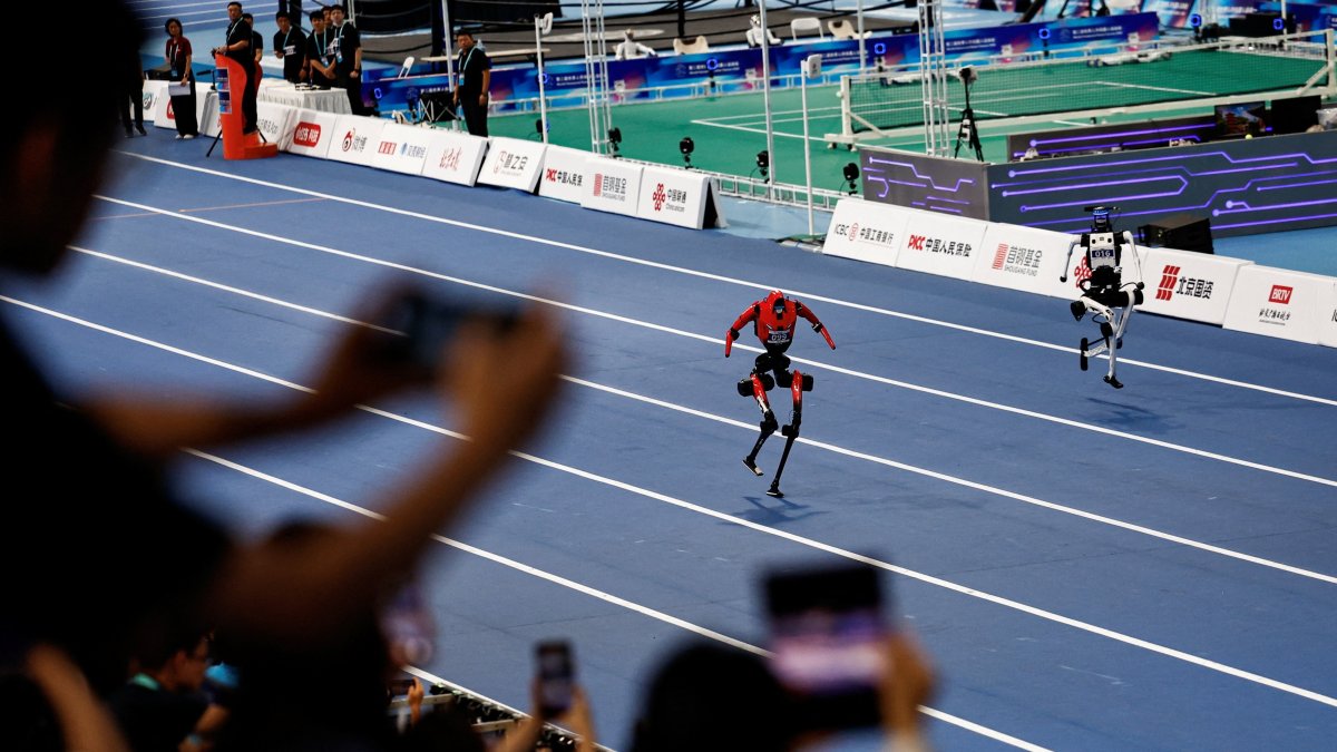 Spectators use smartphones as they watch humanoid robots by Honor and Tiangong compete during a 100-meter large-sized group preliminary race, at the 2026 World Humanoid Robot Games, in Beijing, China, Aug. 22, 2026. (Reuters Photo)