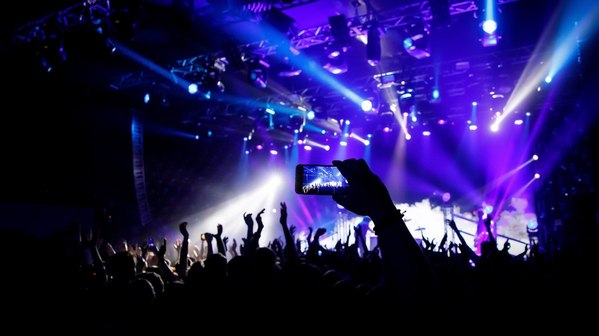 A person filming a concert on mobile phone camera. (Shutterstock Photo)