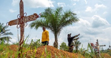 Charles Mambo, the supervisor at the Ceca-20 cemetery, flanked by the assistant warden of the cemetery, stands, Mungwalu, Ituri province, Democratic Republic of Congo, July 14, 2026. (Reuters Photo)