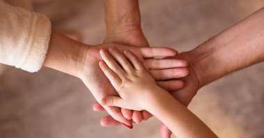 Four hands come together, symbolizing family unity. (Shutterstcok Photo)