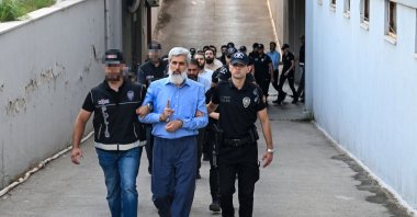 Police officers escort Alparslan Kuytul to the courthouse after his detention, Adana, southern Türkiye, Aug. 22, 2026. (AA Photo)